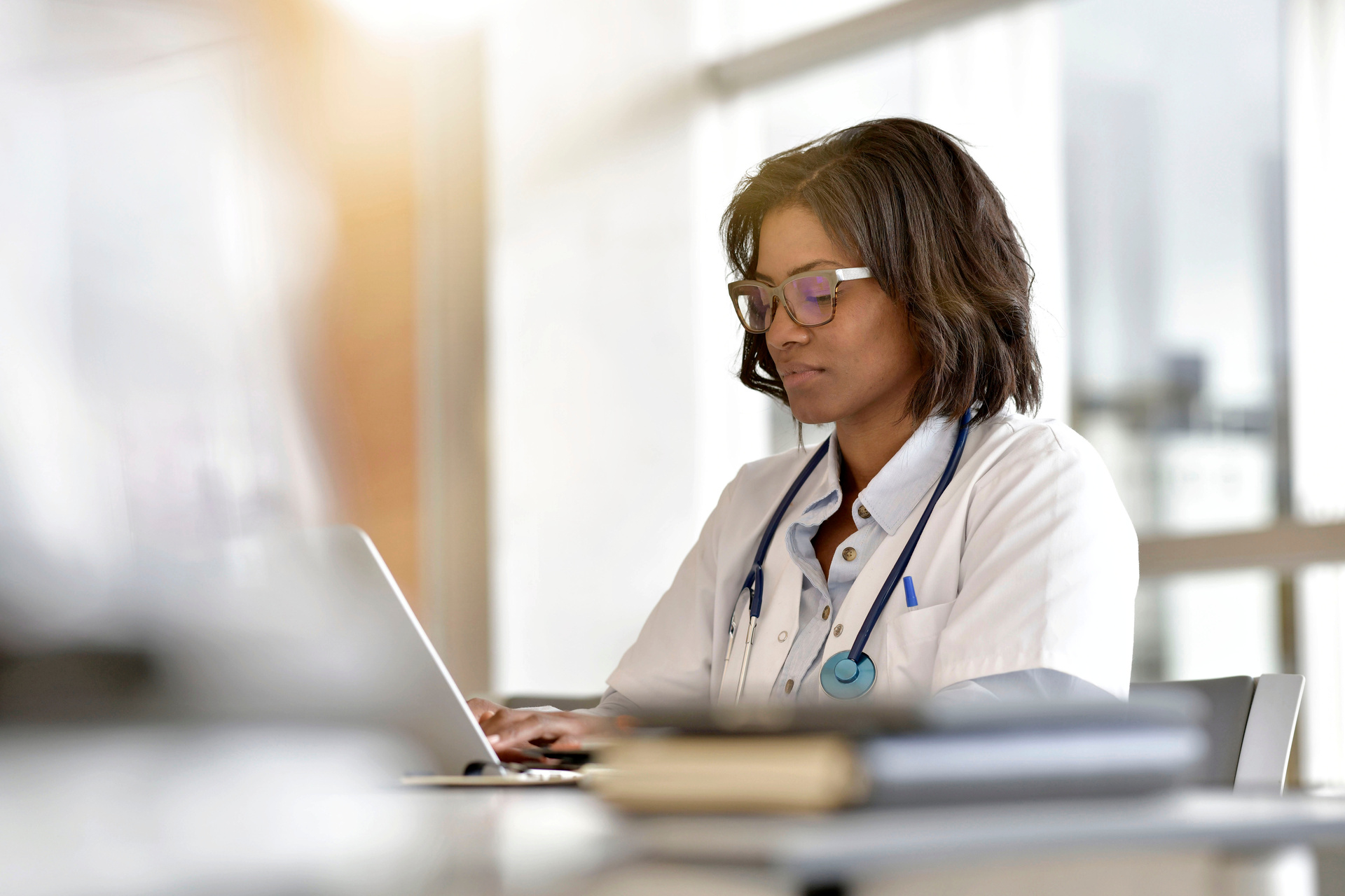 Black female medical professional working at a laptop