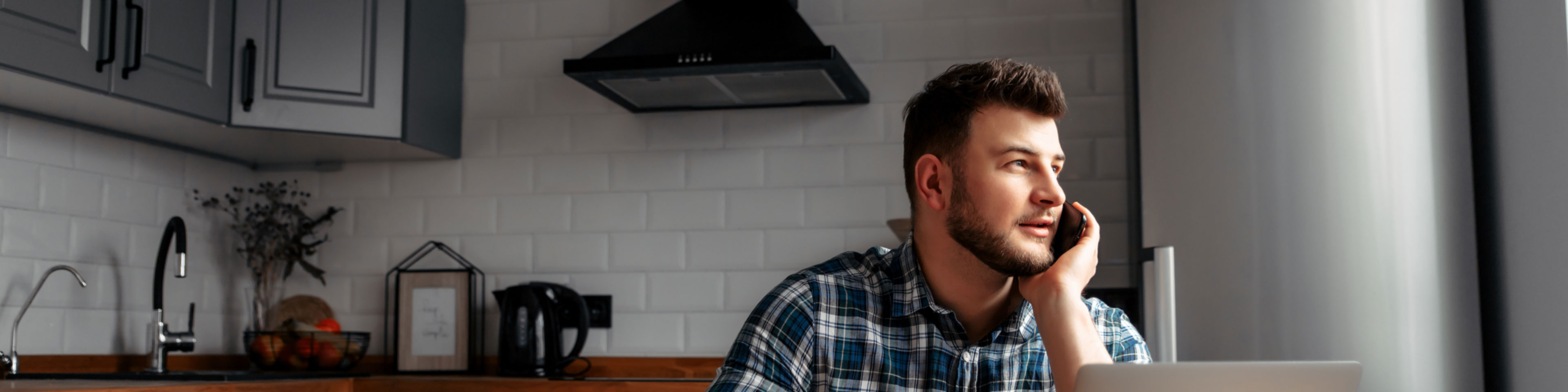 Man working from his kitchen talking on his phone