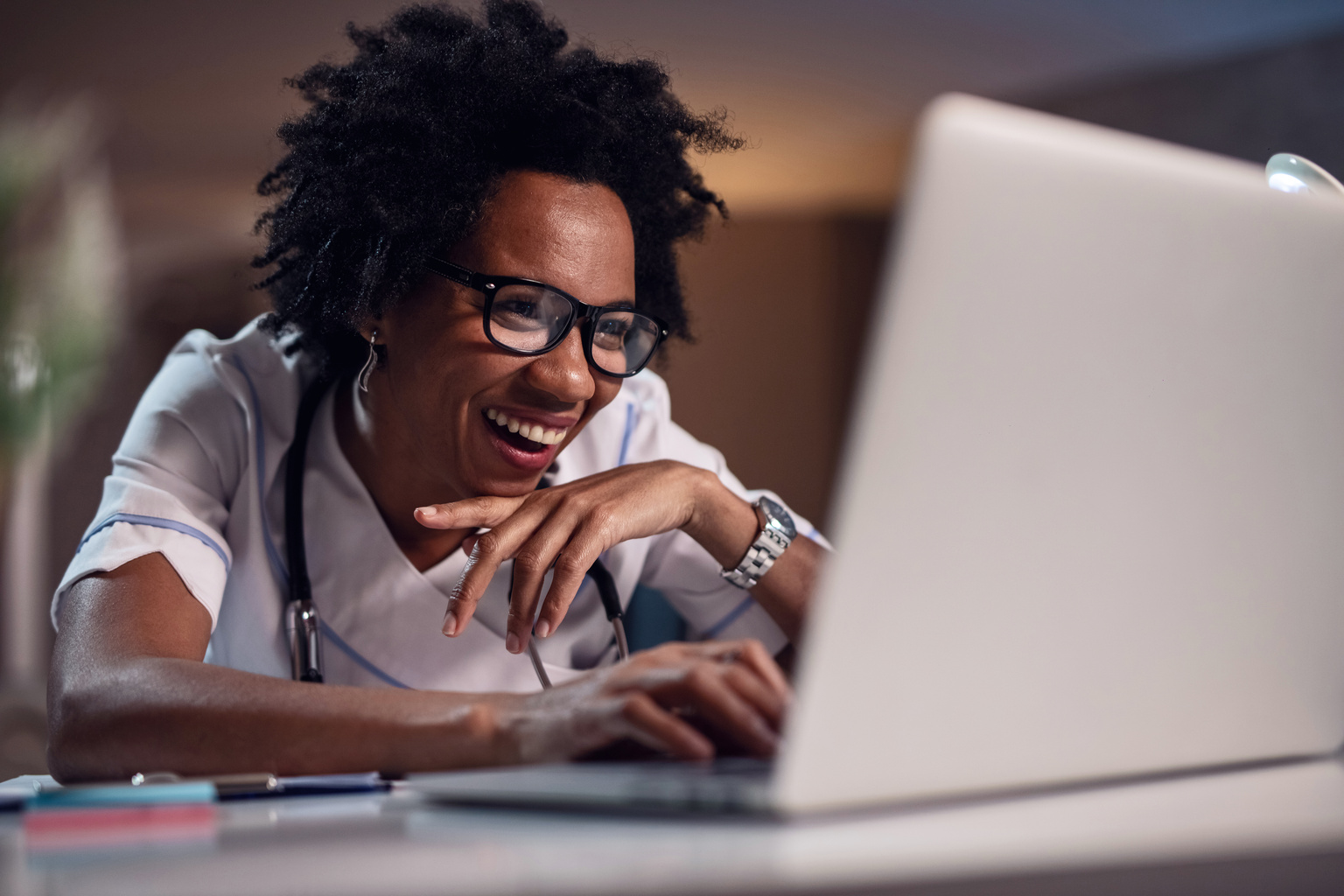 Happy black female doctor surfing the internet on laptop