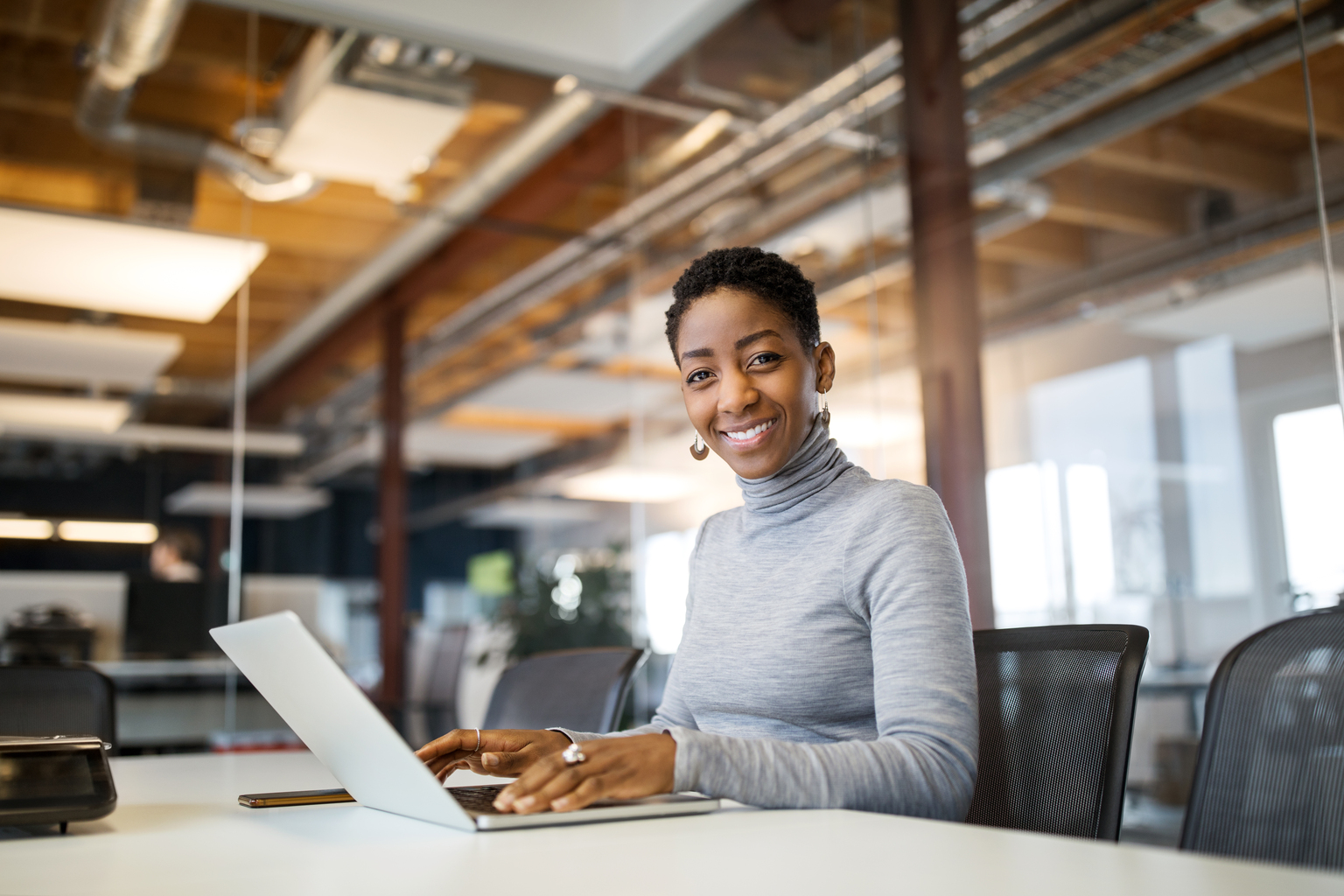 Portrait of mid adult woman using laptop. Confident female professional is sitting at boardroom table with laptop computer.