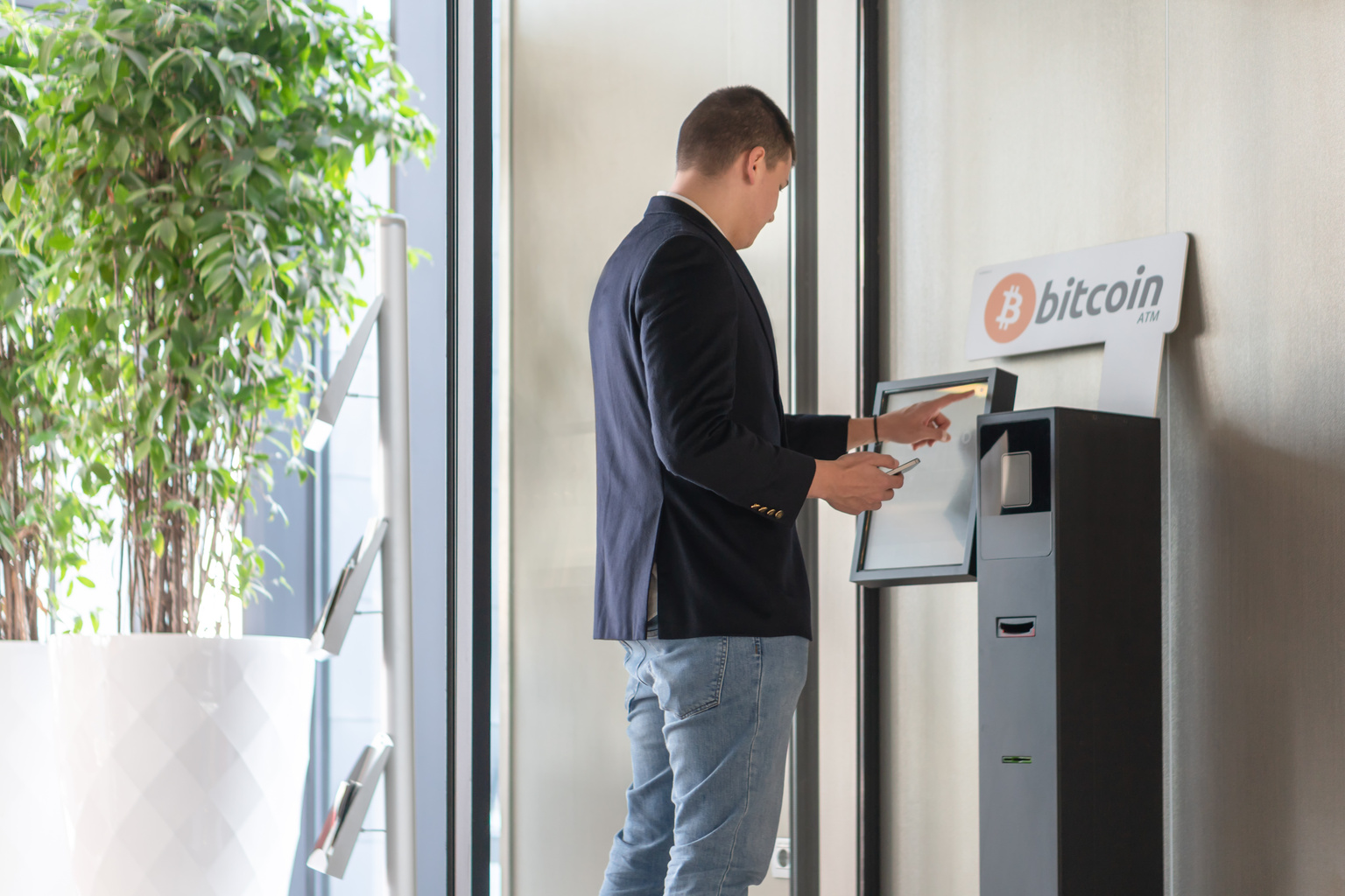 Young businessman buying cryptocurrency on ATM machine for buying and selling cryptocurrency.