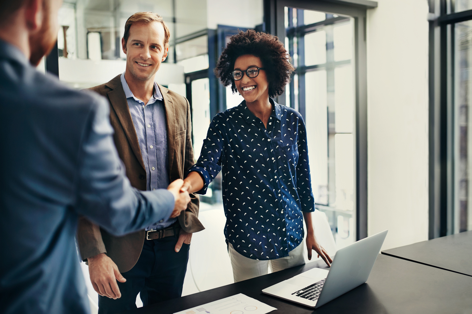 Shot of colleagues shaking hands during a meeting at work