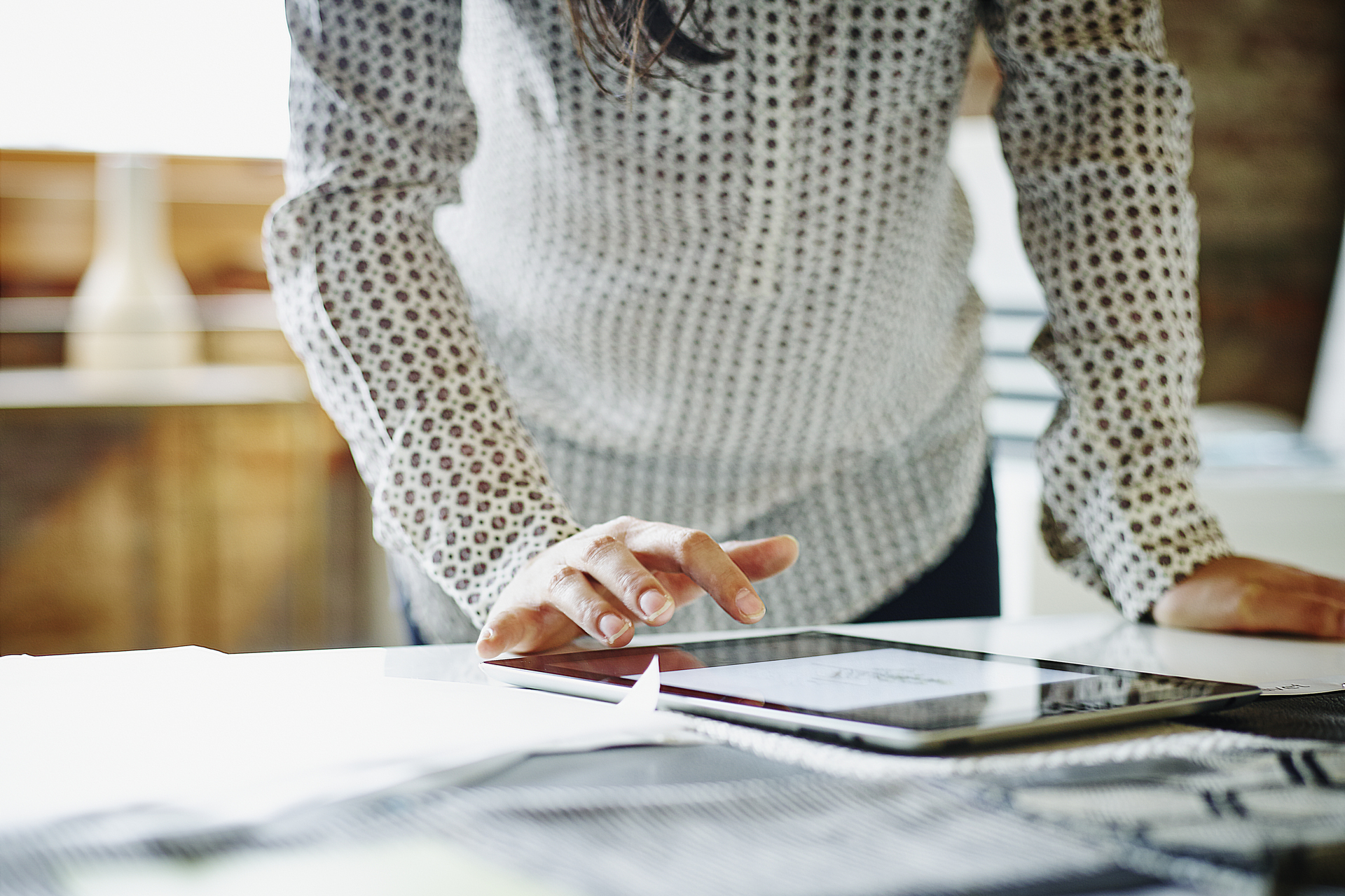 Focus imagery shot of woman looking at architectural plans on tablet, ipad, wearing a white and brown polka dot dress shirt, wood, Q3 2021, TAA NA US - Preparer