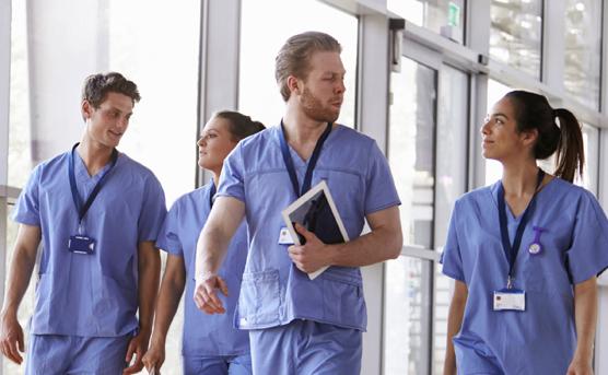 Four healthcare workers in scrubs walking in corridor