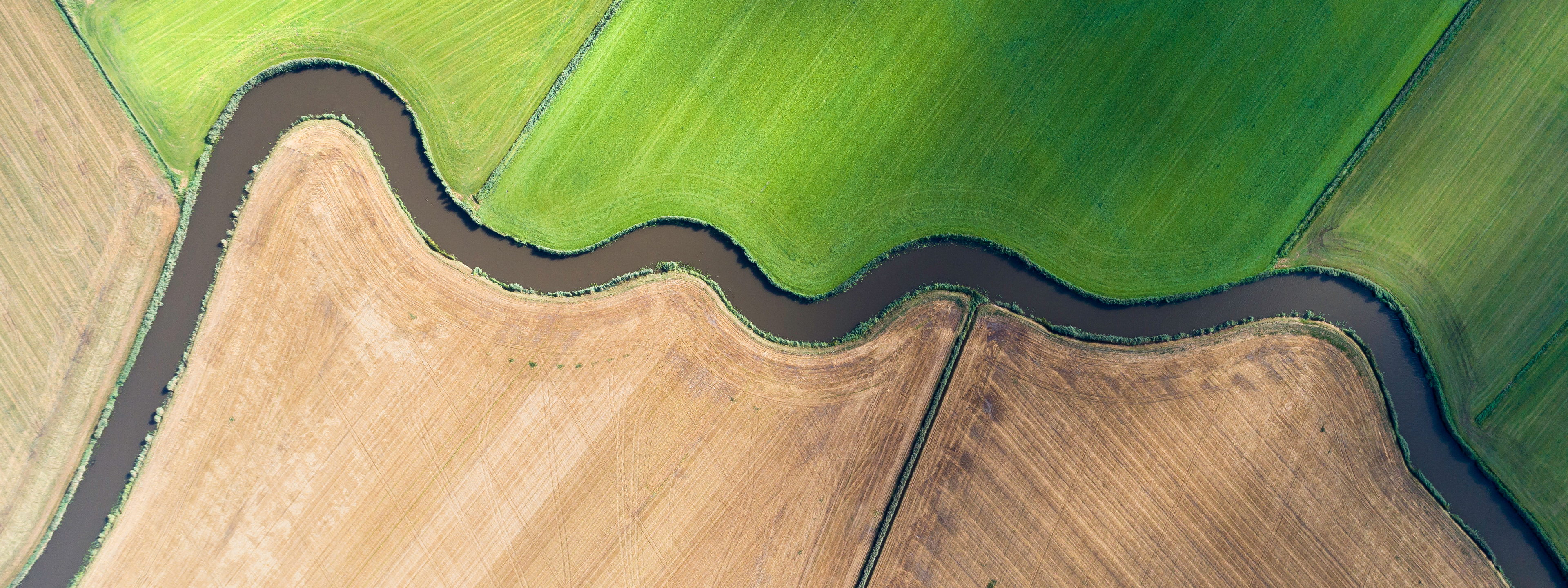 Aerial view of river bending through cultivated fields