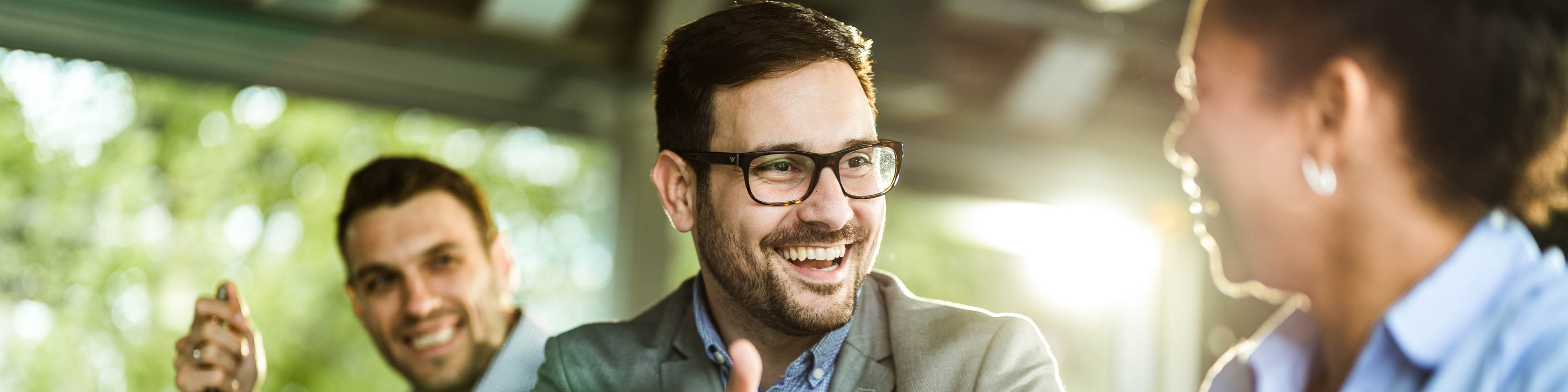 Happy businessman talking to his female colleague while working on laptop in the office.