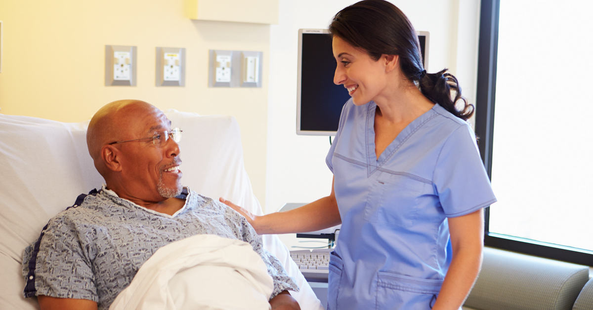 Nurse in blue scrubs at patients bedside providing care