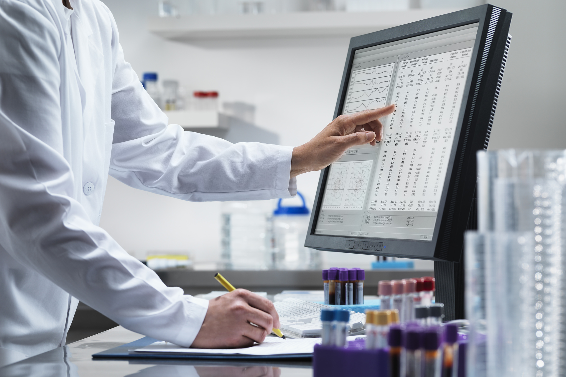 Scientist pointing to computer monitor in lab.