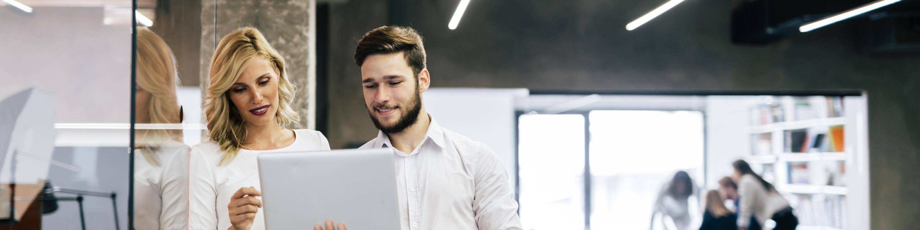 two people in business casual clothing looking at a laptop