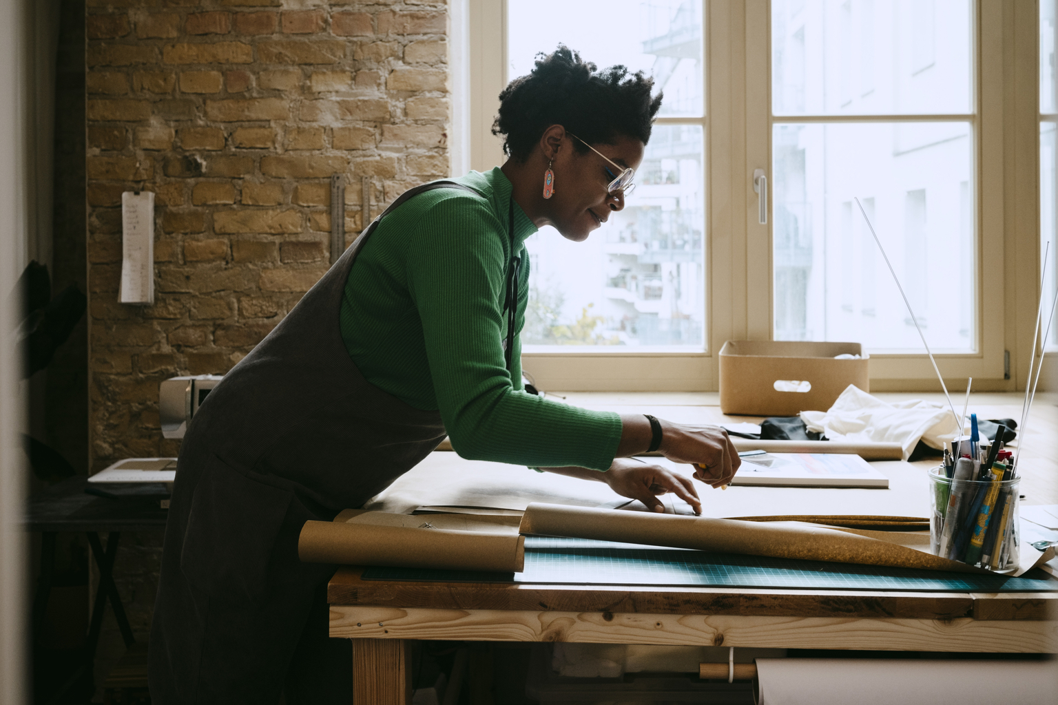 Female artist concentrating while doing craft at table in living room