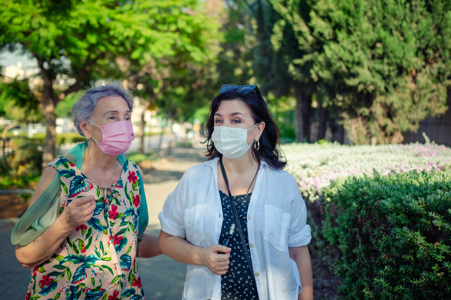 Older woman and middle-aged woman walking outside, both wearing masks