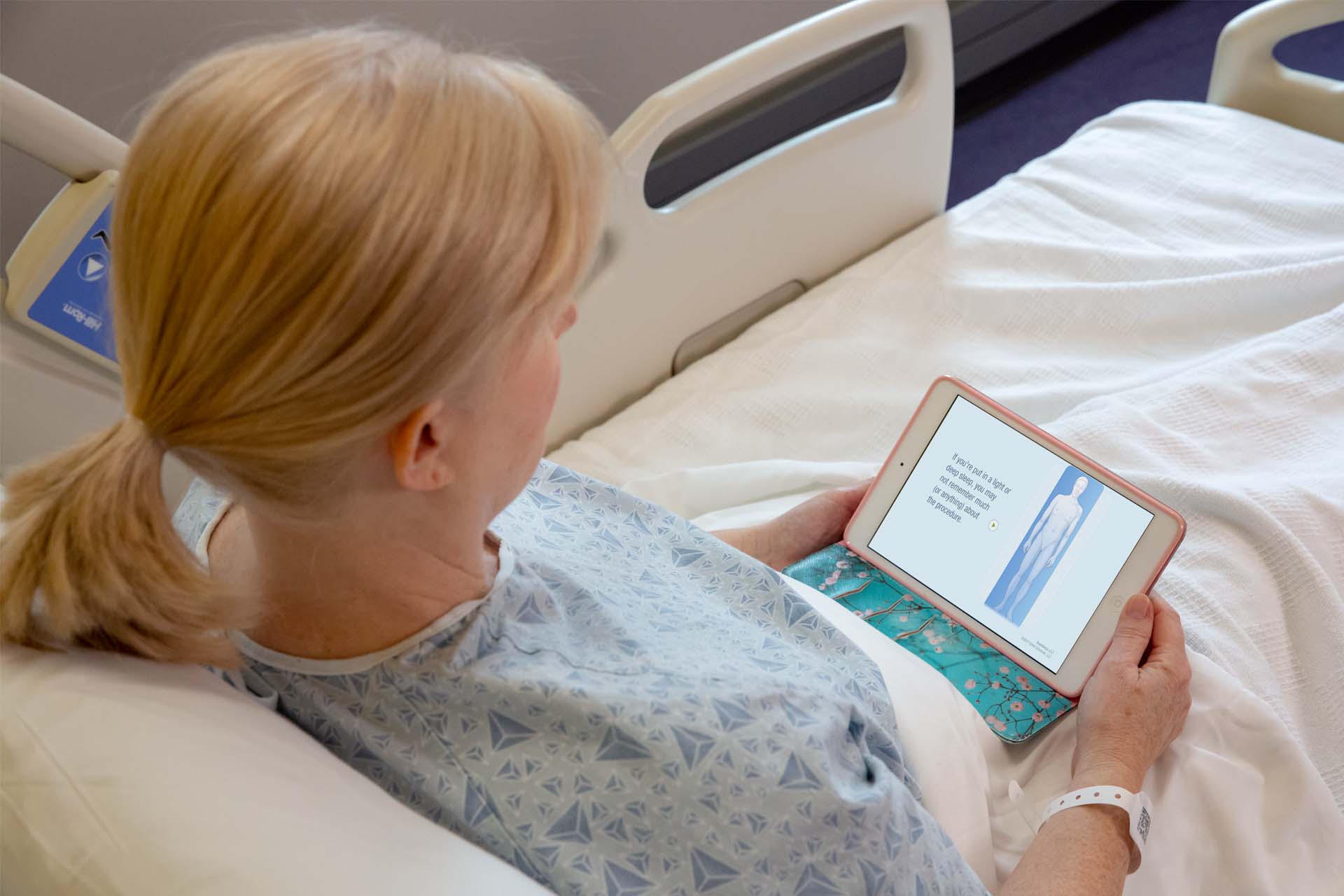 female patient in hospital bed with tablet