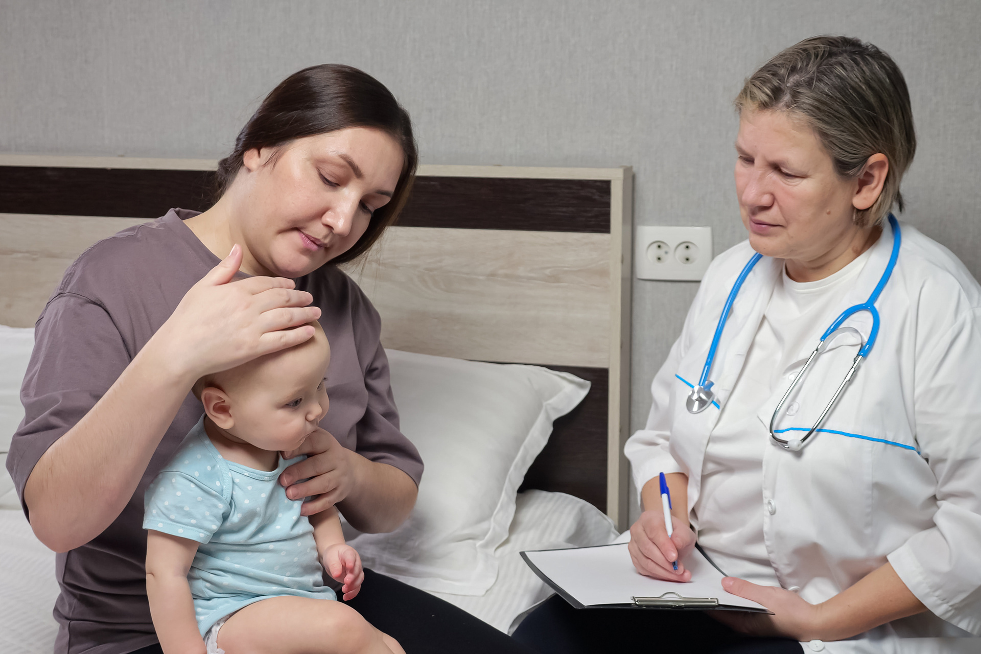 Doctor providing exam to a small infant sitting in the mother's lap