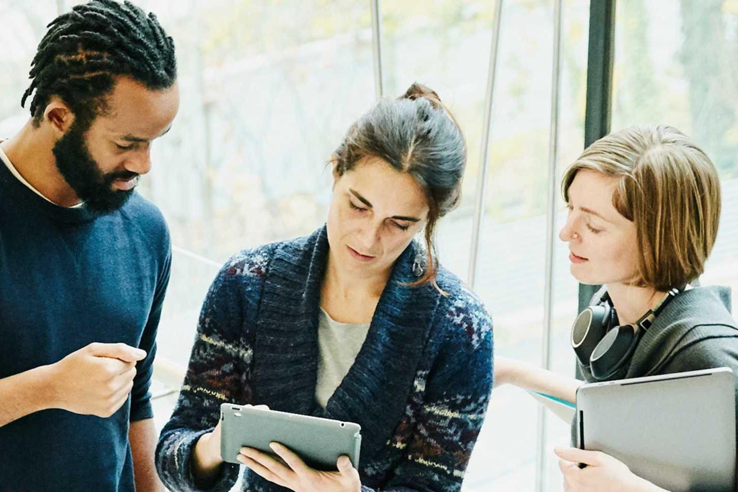 Man and two women reviewing tablet in office stairway