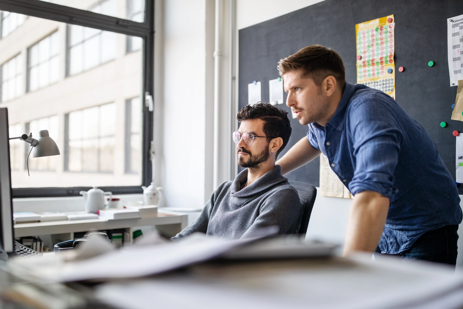 Two male colleagues working together looking at the screen