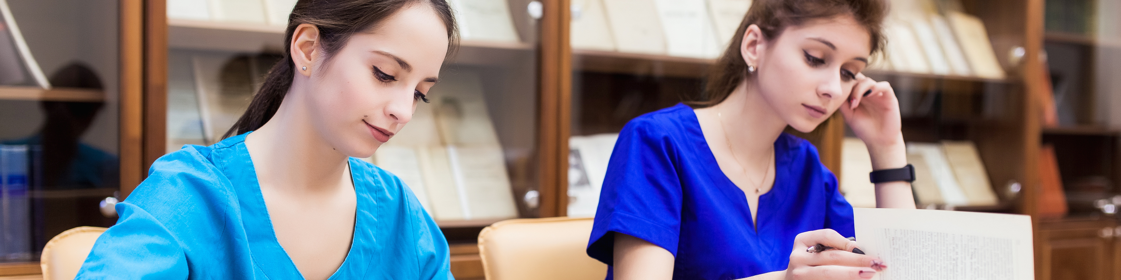 Two medical students searching through textbooks in nursing school