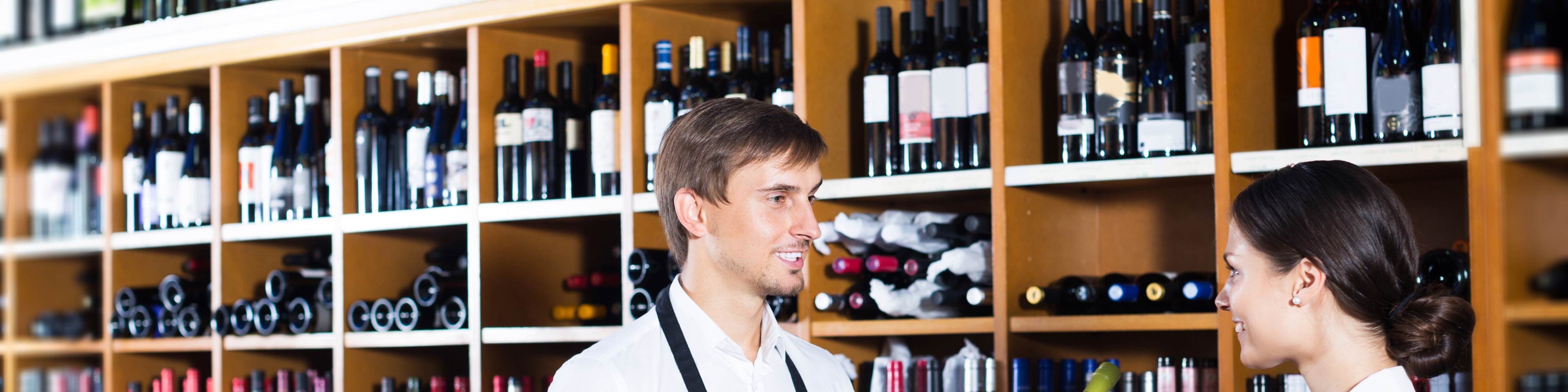 Two people standing in a liquor store, picking out a bottle of wine