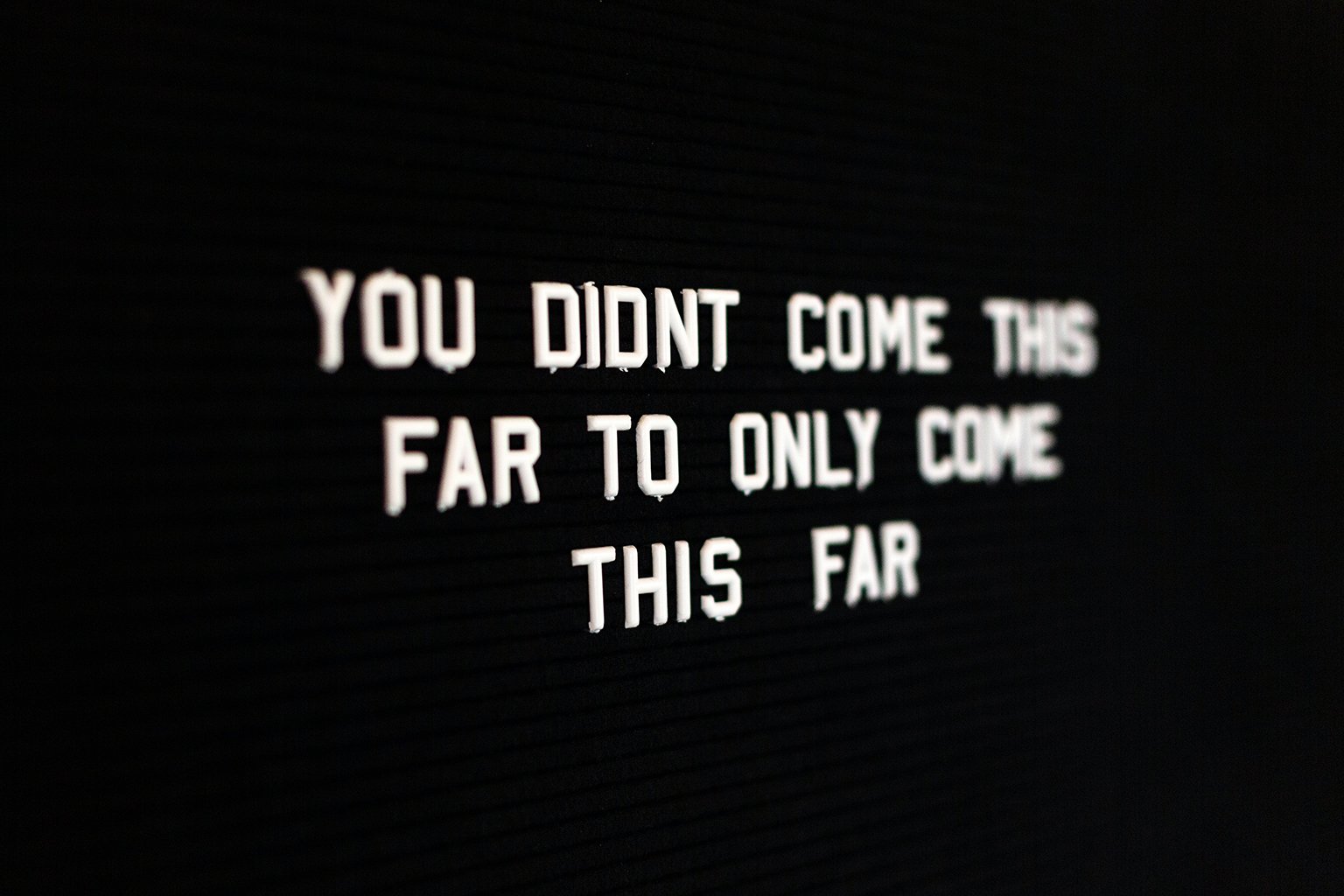 Black bulletin board with white letters saying: You didn't come this far to only come this far