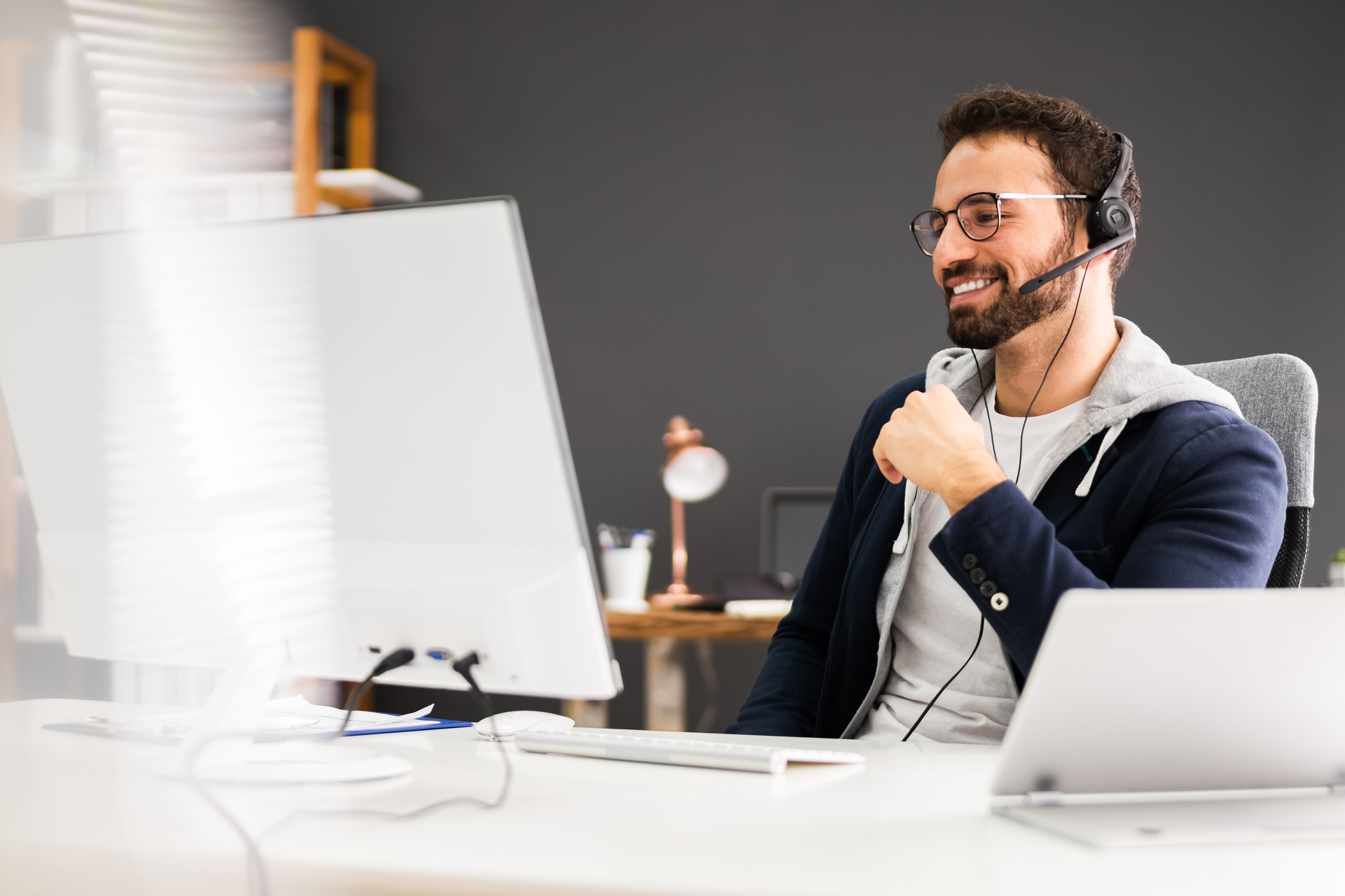 Person sitting at laptop, wearing headset conducting a business call