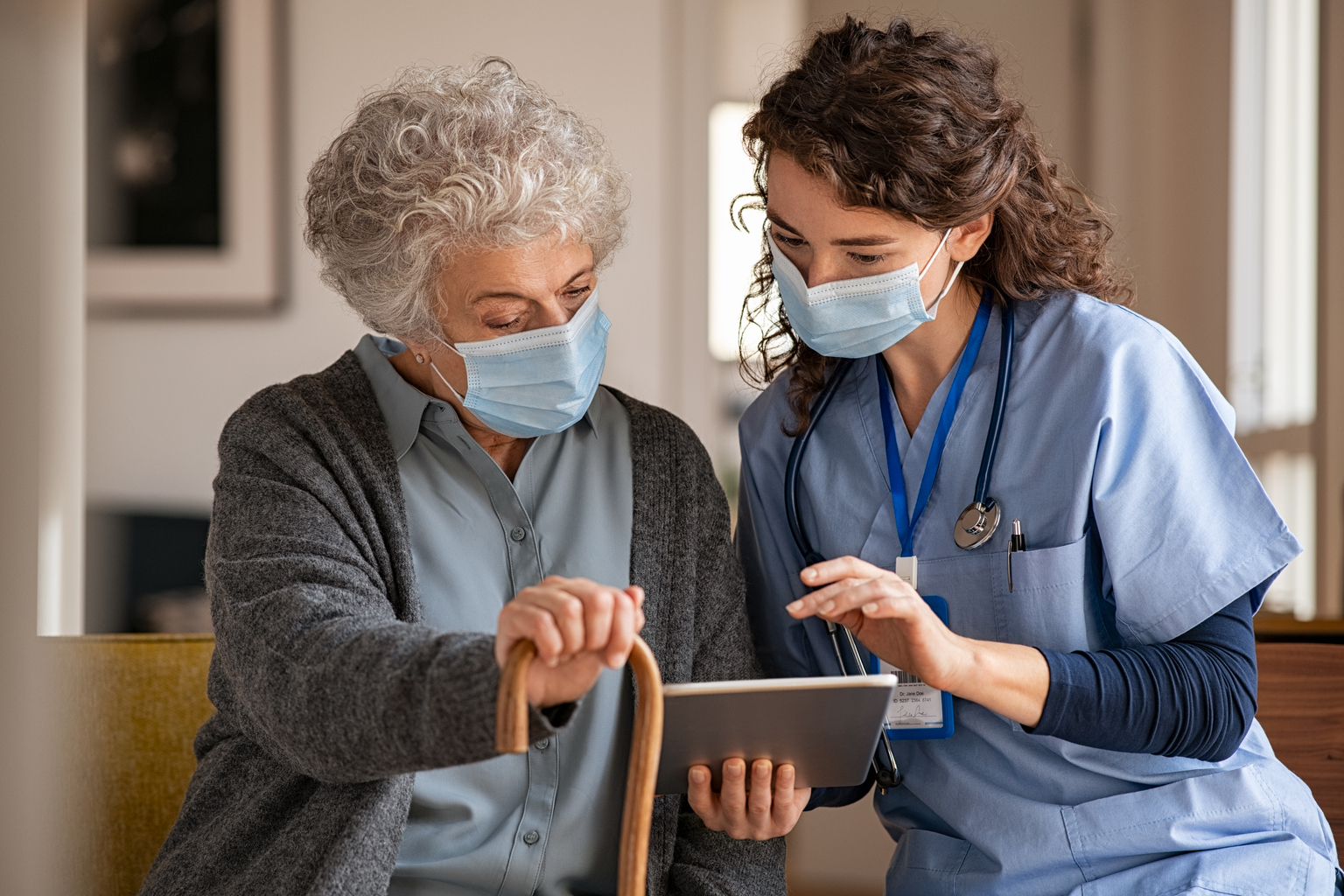 Patient wearing mask watching education video on tablet with nurse