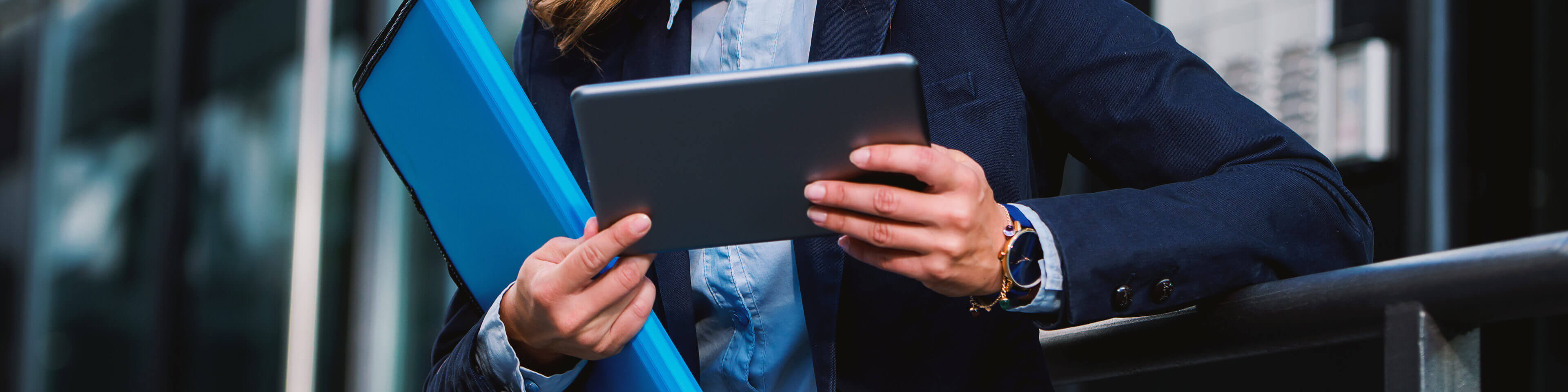 woman in business attire outside holding a tablet