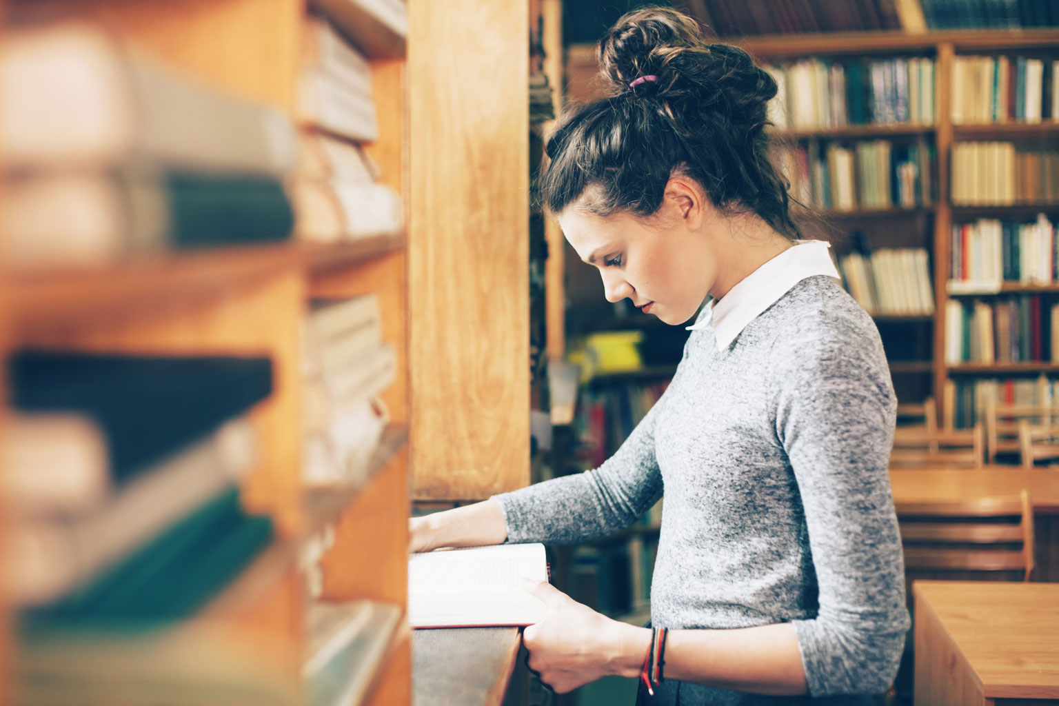 Studentka szkoły wyższej przegląda książkę w bibliotece