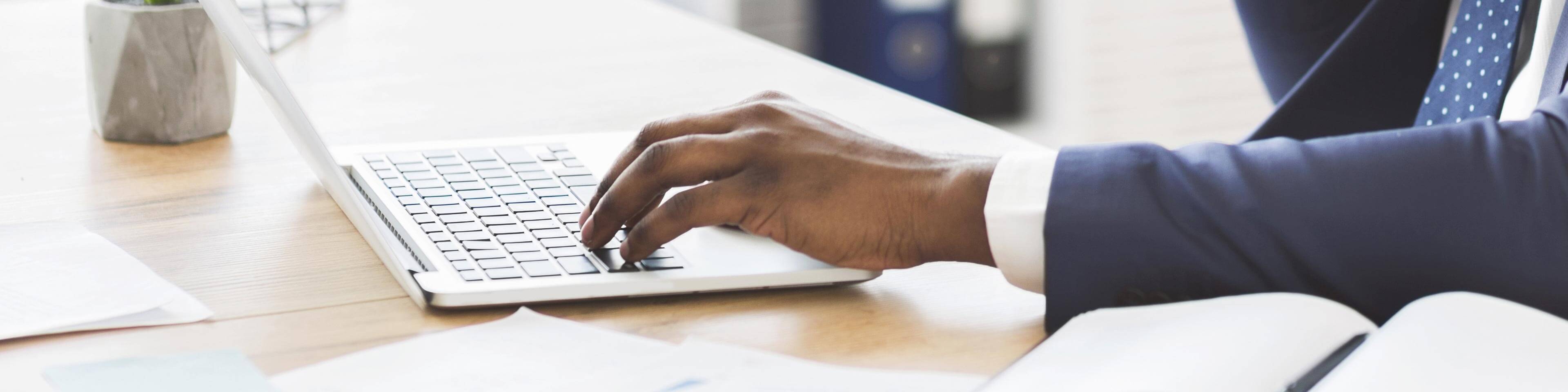 Man in a blue suit typing on a computer.