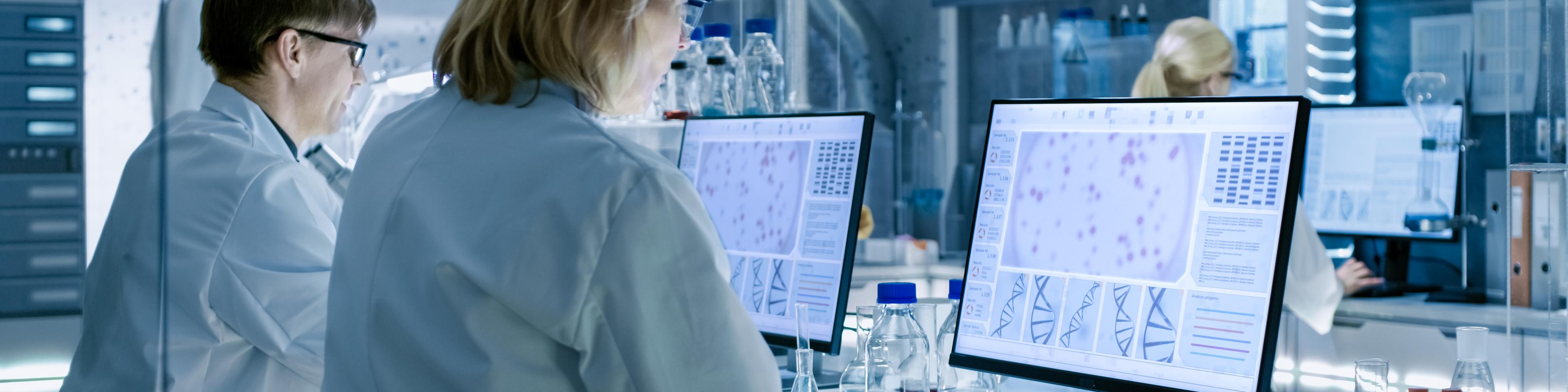 Female and Male Scientists Working on their Computers In Big Modern Laboratory