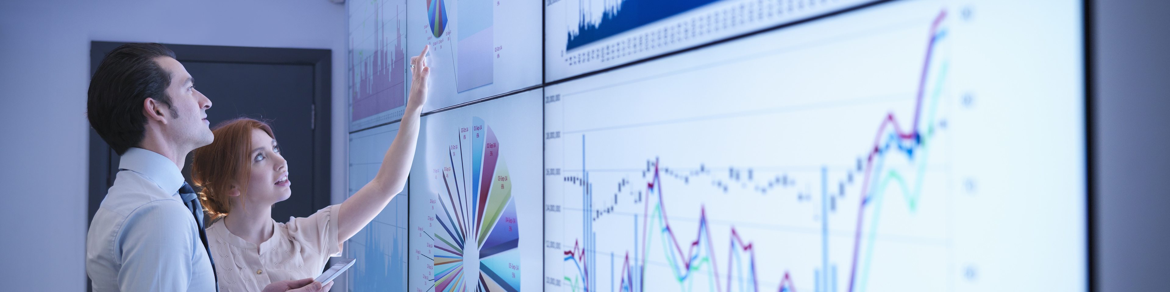 Business colleagues studying graphs on screen in meeting room