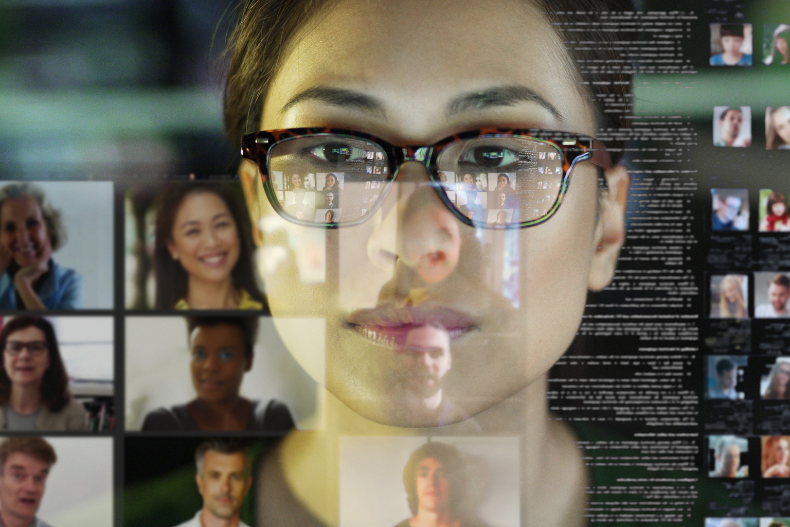 A professional Asian woman, in her office, looking at a see through display with a team of people making a conference call