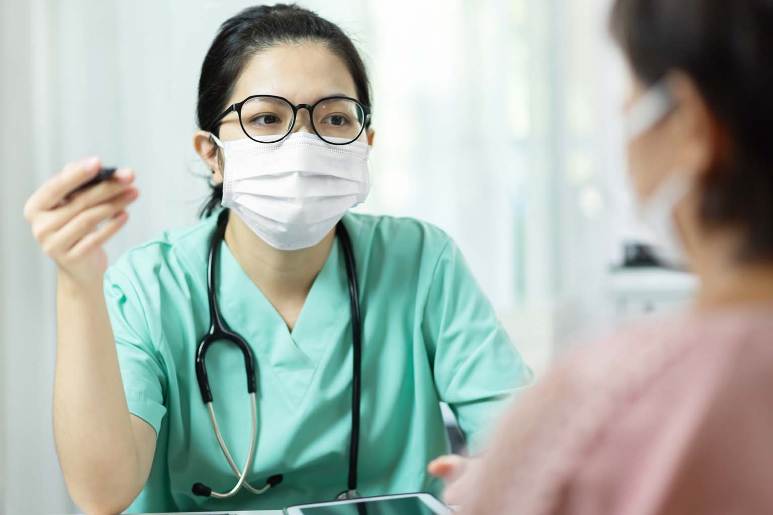 clinician with mask talking to patient