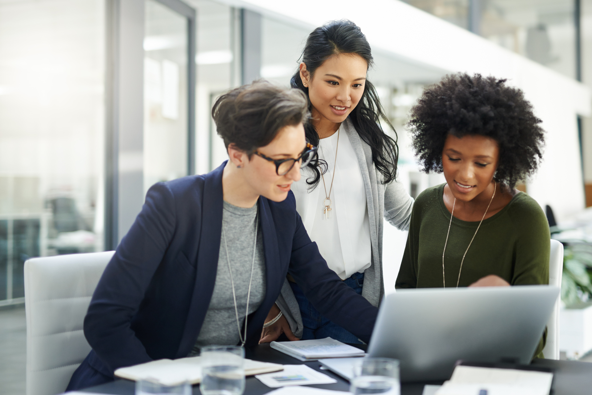 Three Businesswomen smilingly looking at the laptop.