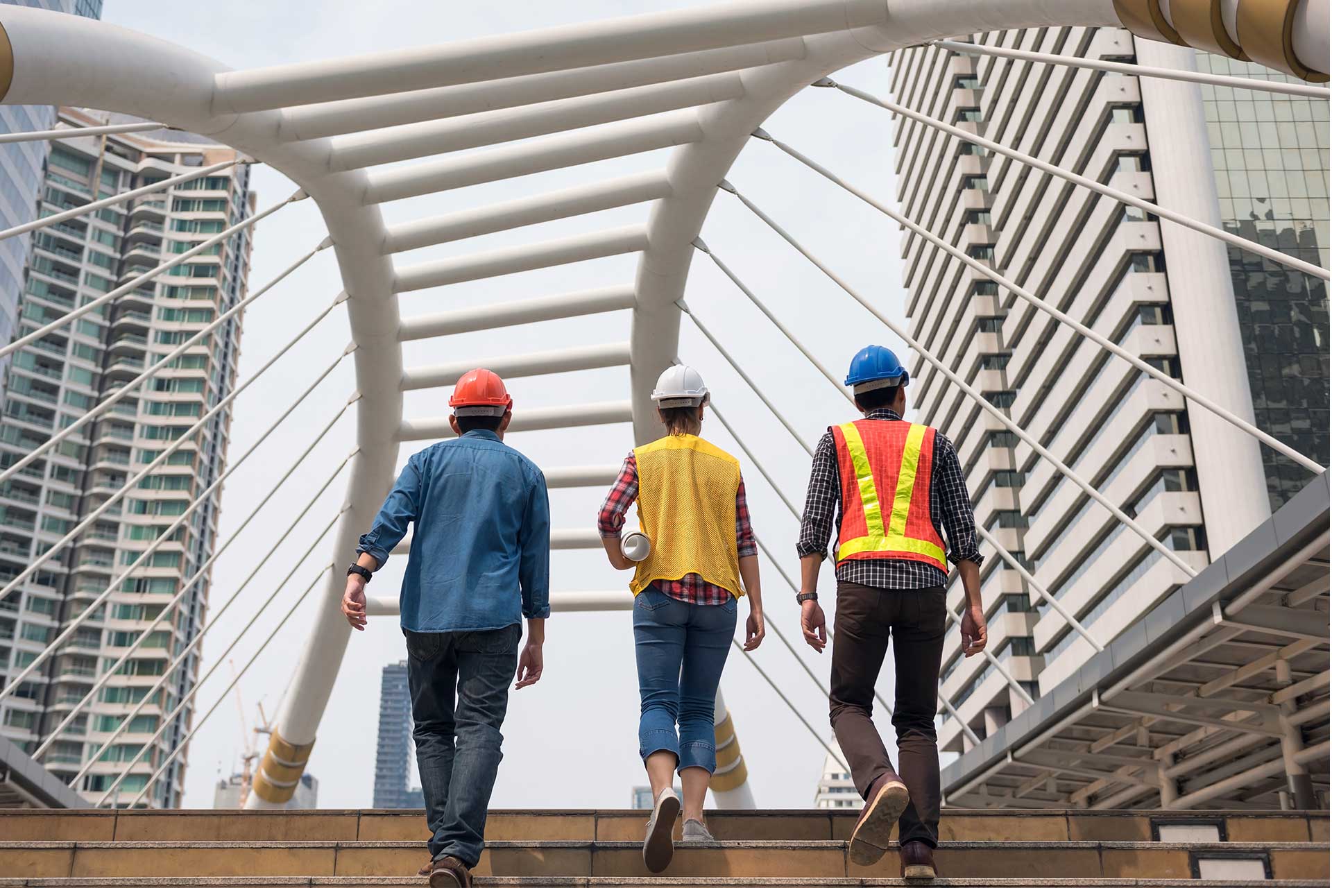 3 contractoren wandelen op een brug in veiligheidkledij