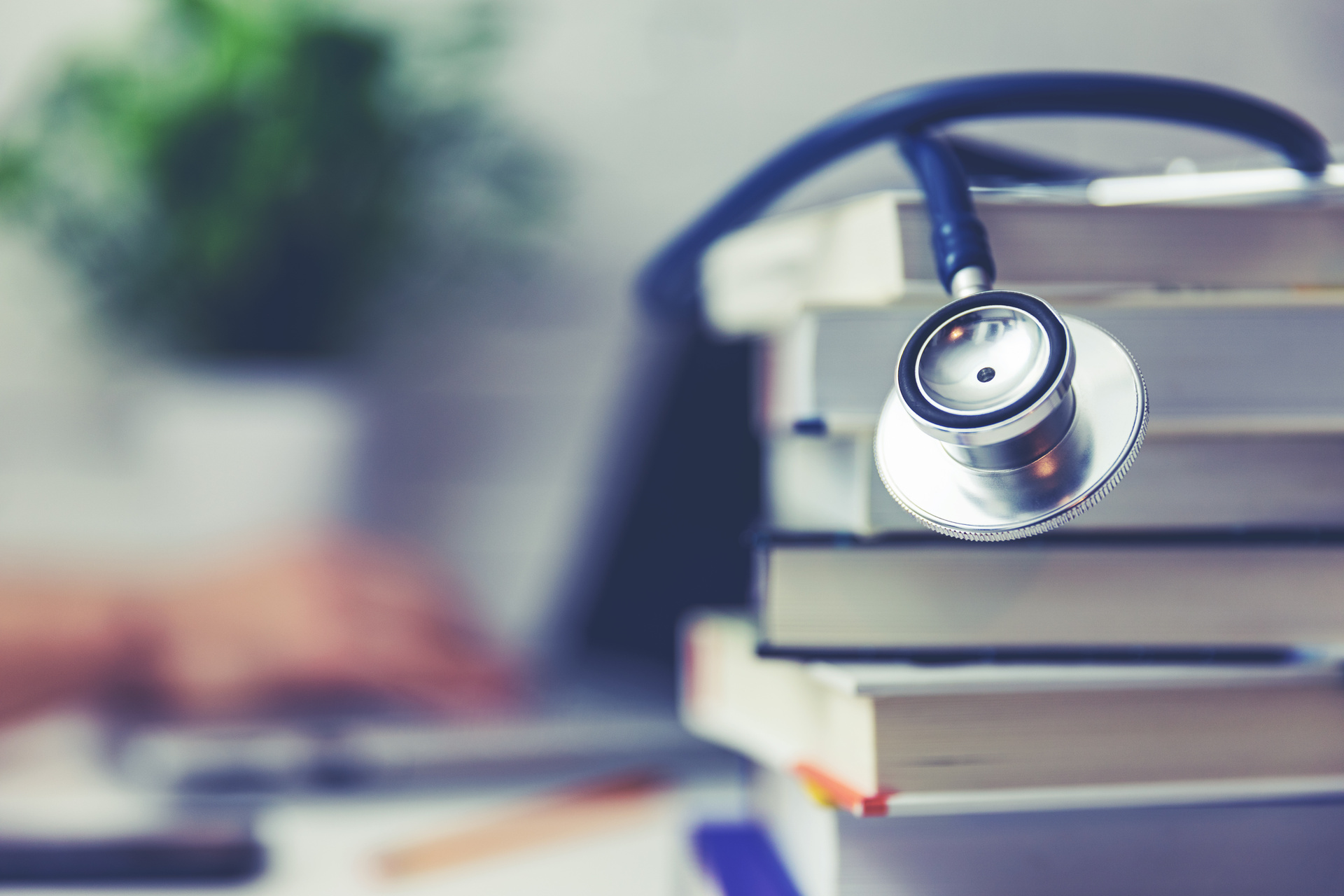 Medical school student studying in the library concept (stethoscope on top of book stack)