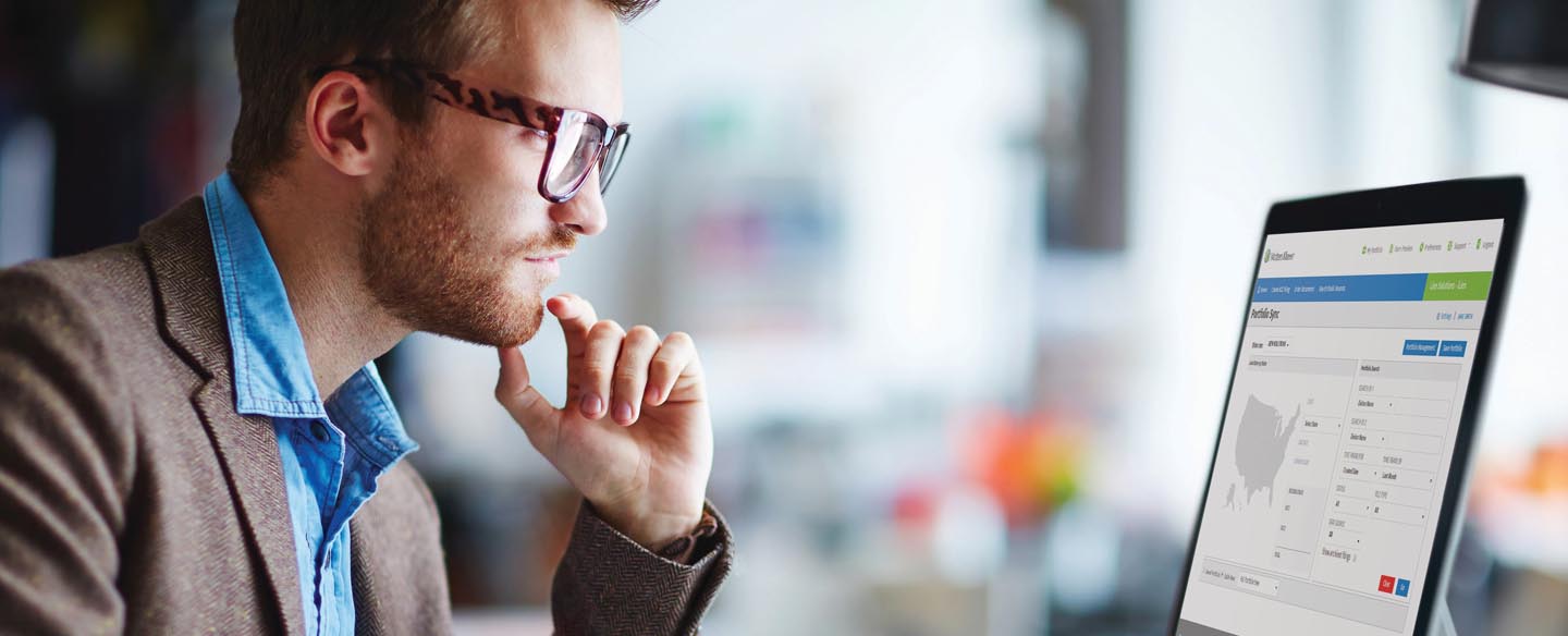 A man looking at a computer, he is syncing up his lien portfolio.