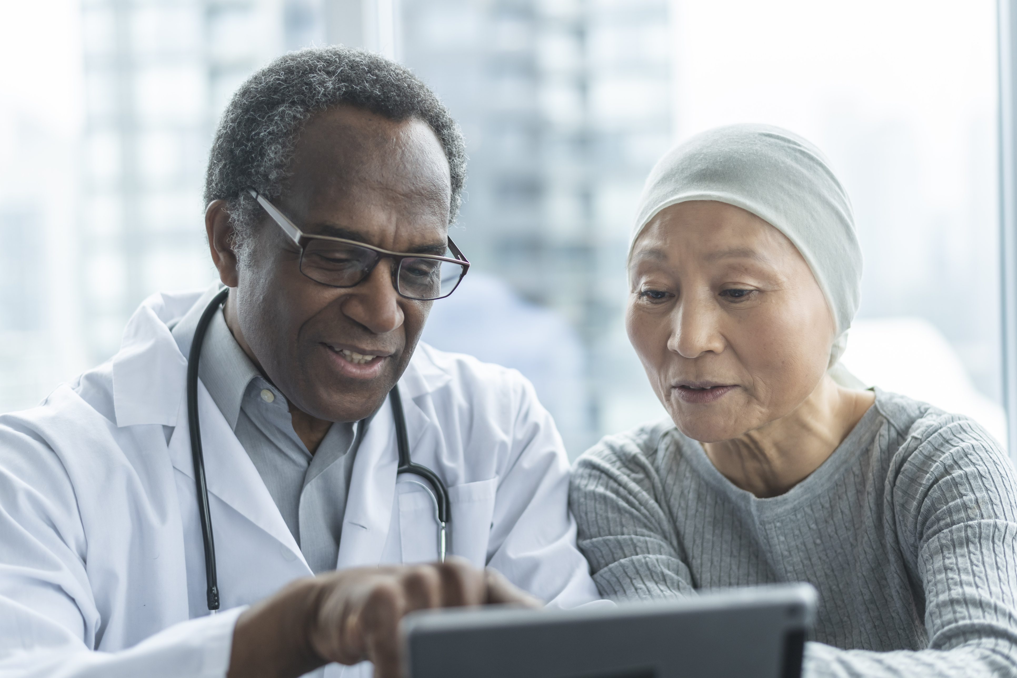 Doctor with cancer patient looking at a tablet