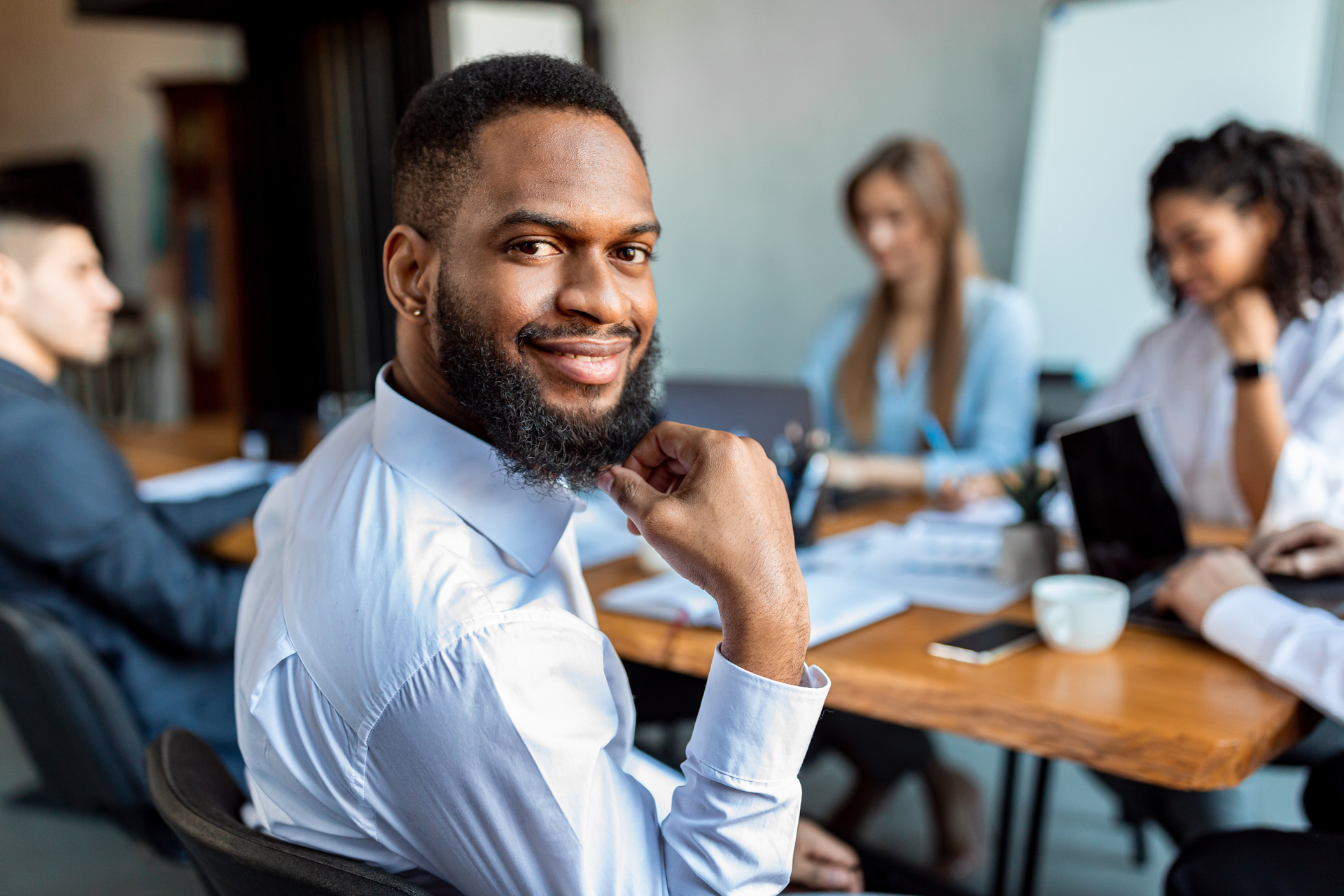 Businessman Sitting Smiling To Camera In Modern Office