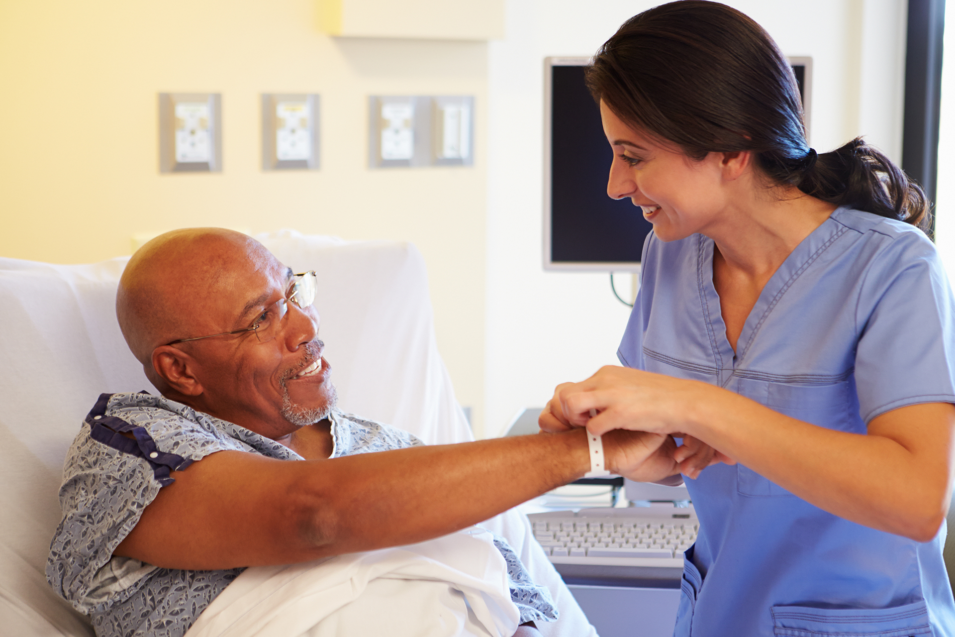 Nurse putting wristband on senior male patient in hospital