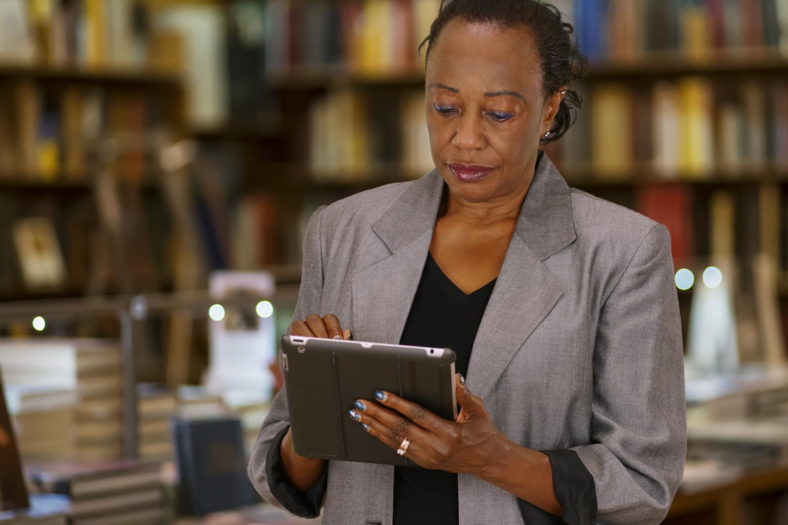 African American woman in library with tablet