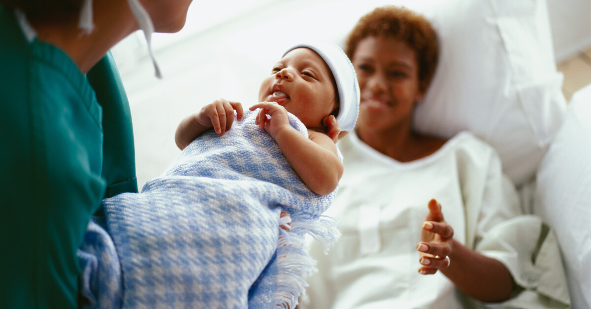 Elevated close-up view of a doctor handing a new born baby to the mother