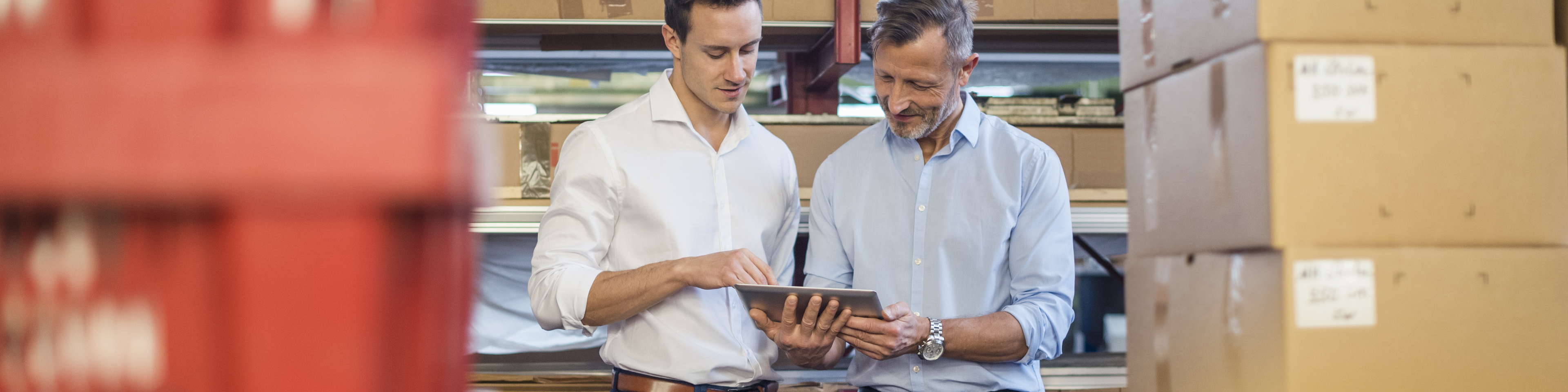 Business people discussing using a tablet at distribution warehouse