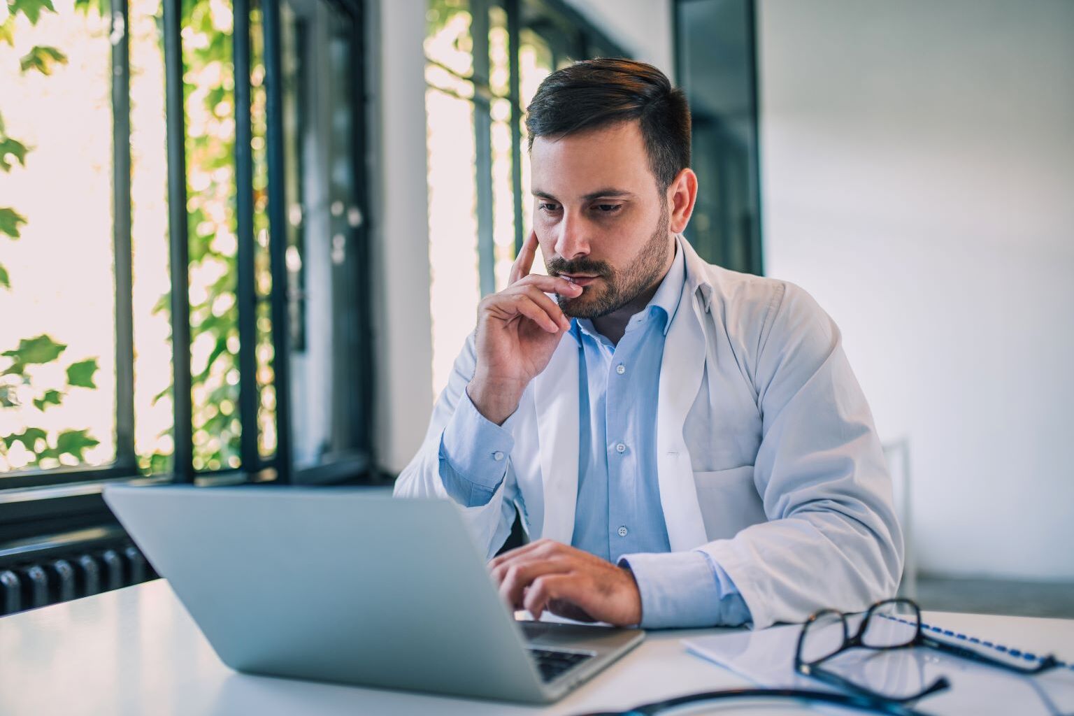 Doctor using laptop at a desk.