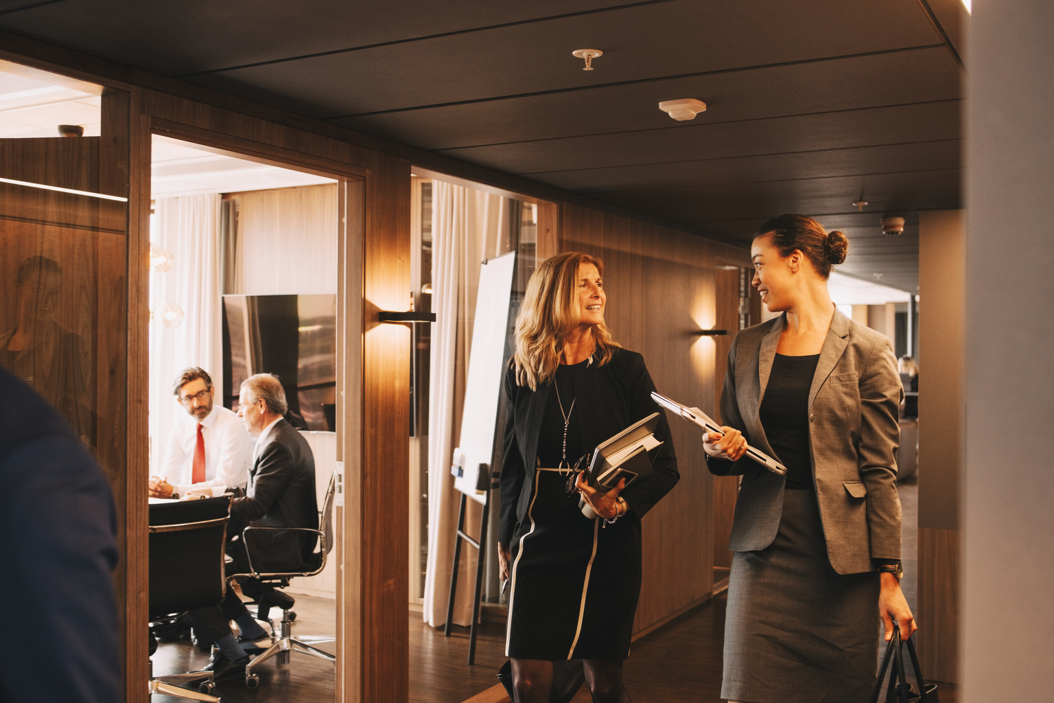 Female lawyers discussing while colleagues planning in background at law office 