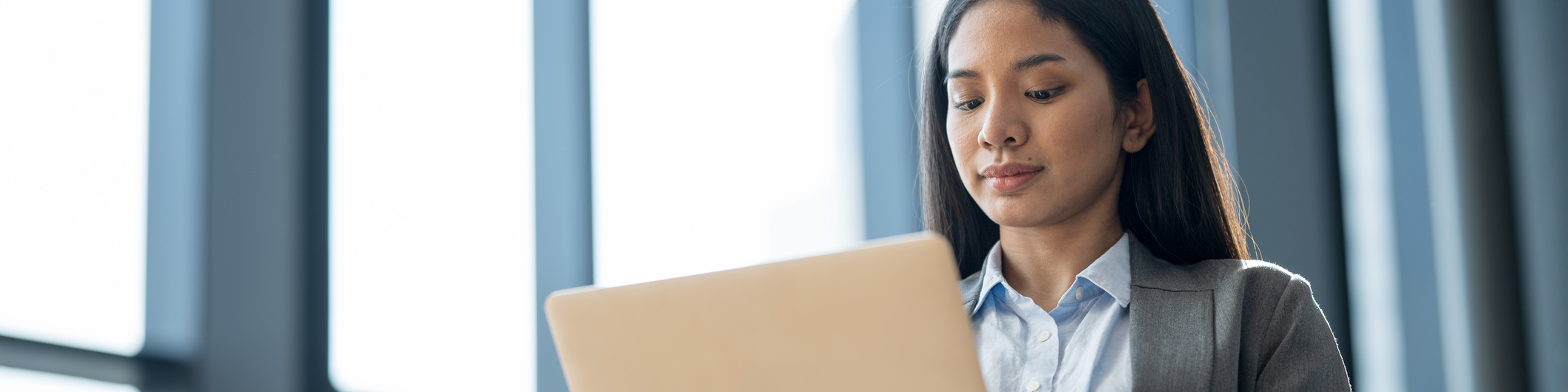 Low-angle view of an Asian businesswoman using a laptop computer to coordinate work with her team in a modern business office