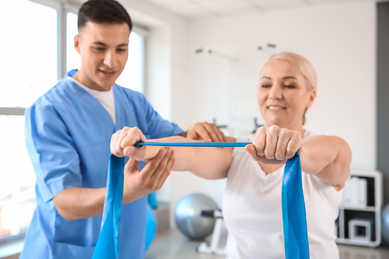 Physiotherapist helping patient with strengthening arms