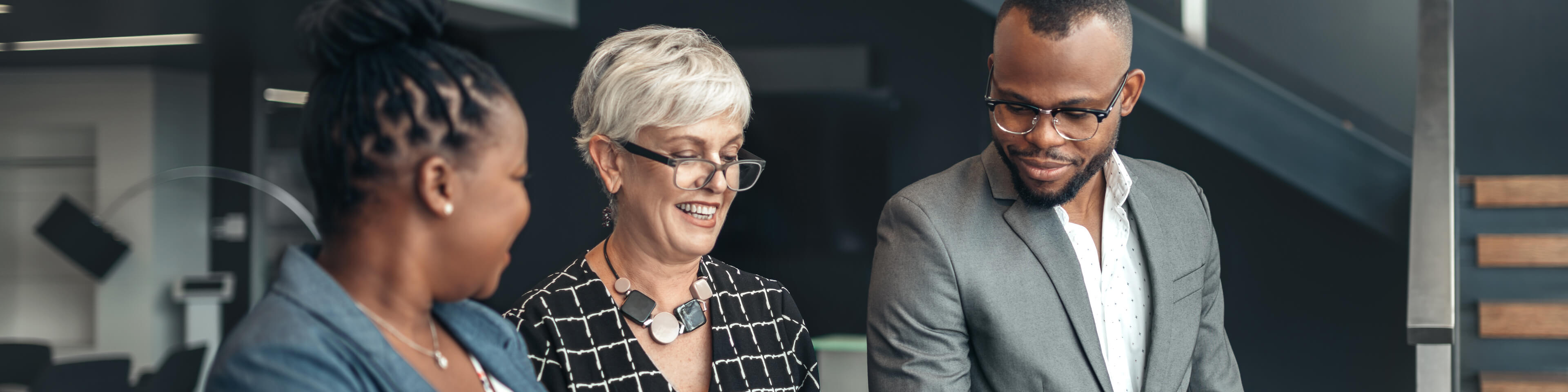 two women and a man wearing business attire talking