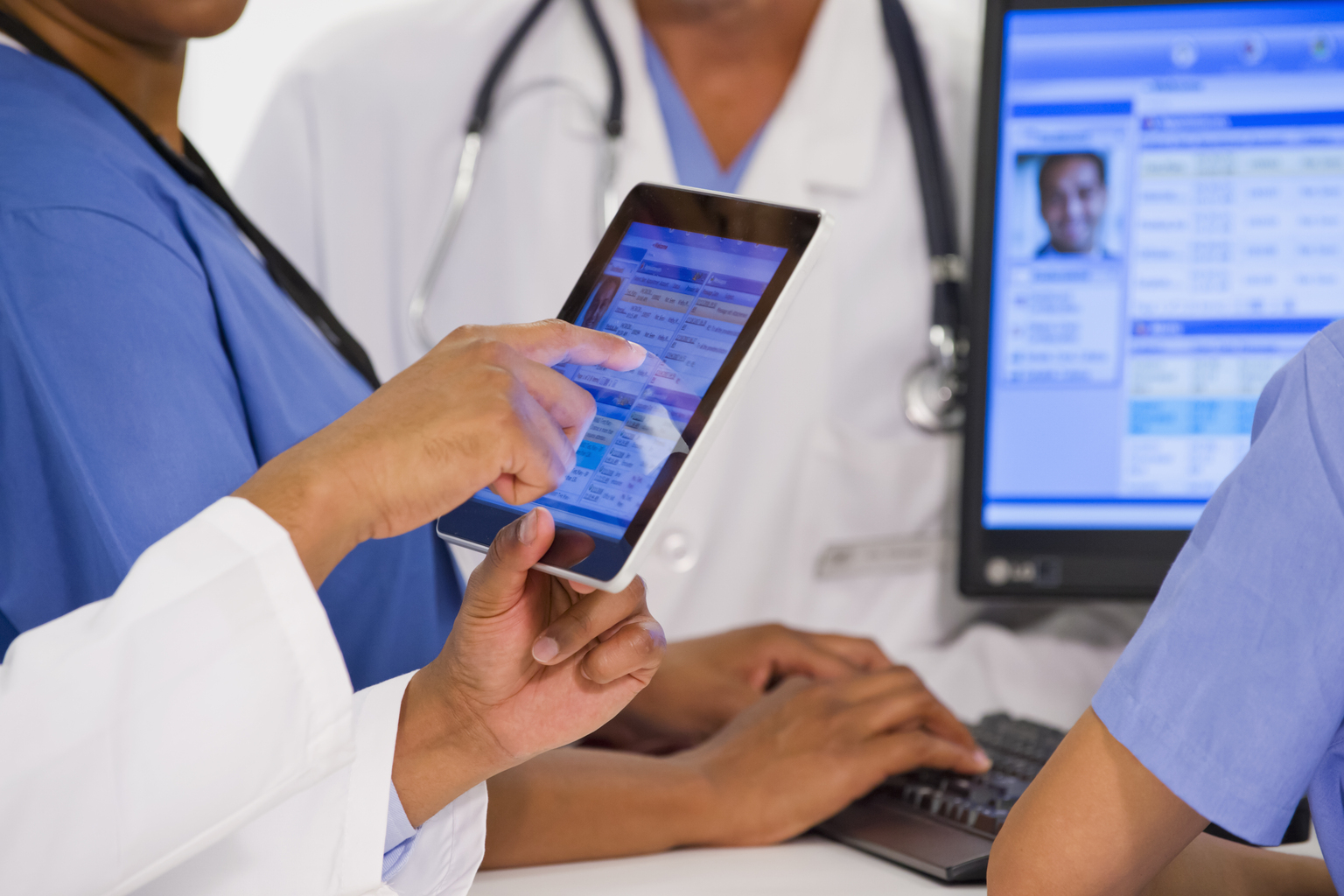 Doctors using digital tablet together in hospital