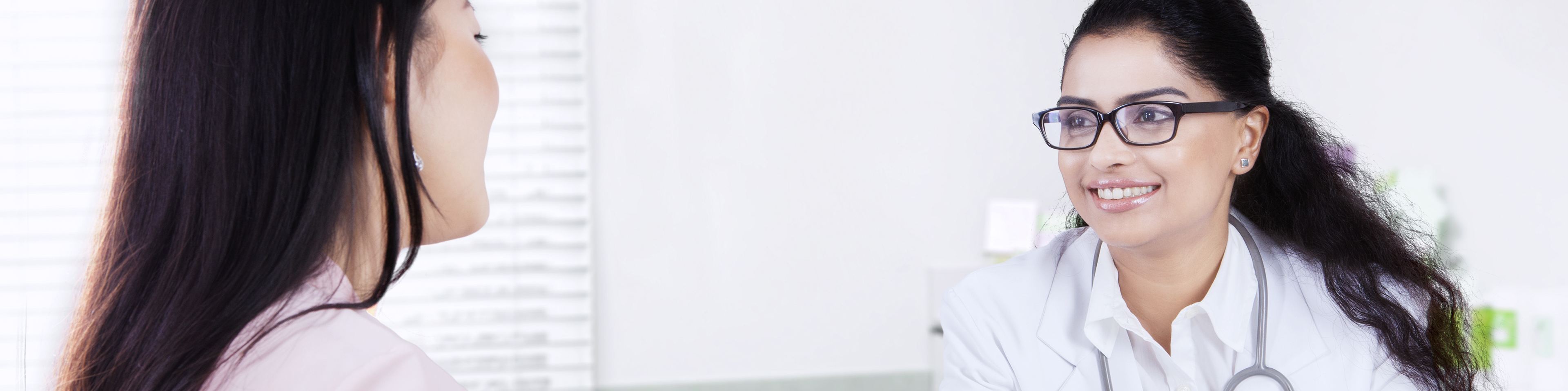 Doctor sitting with and smiling at patient while taking notes