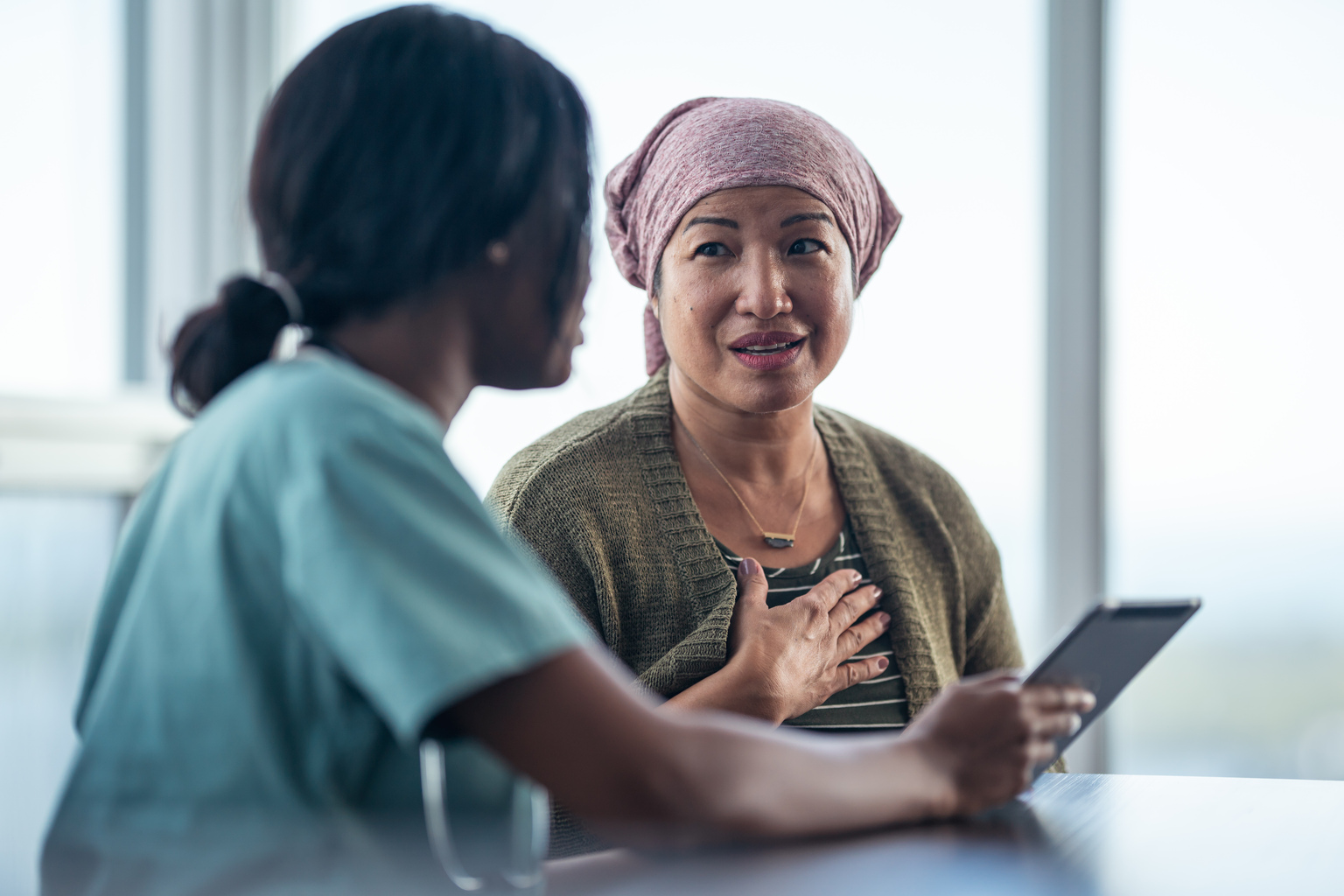 Asian woman with cancer meeting with African female physician