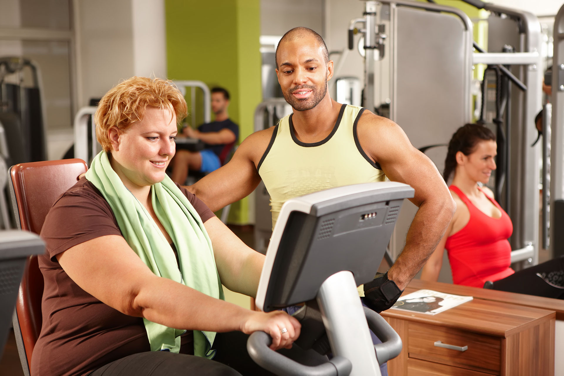 Male personal trainer working with a female client on a stationary bike